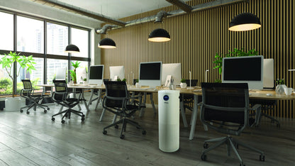 Surgically Clean Air JADE 2.0 air purifier standing in an open-plan office beside a workstation